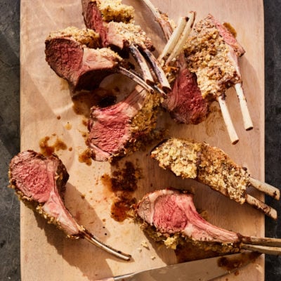 Lamb with Dijon and panko crust on a cutting board.