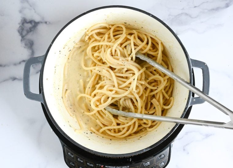 tossing pasta with sauce over low heat