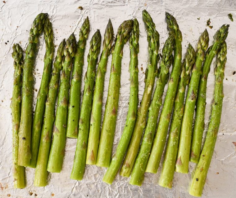 Roasted asparagus on aluminum foil-lined baking sheet.