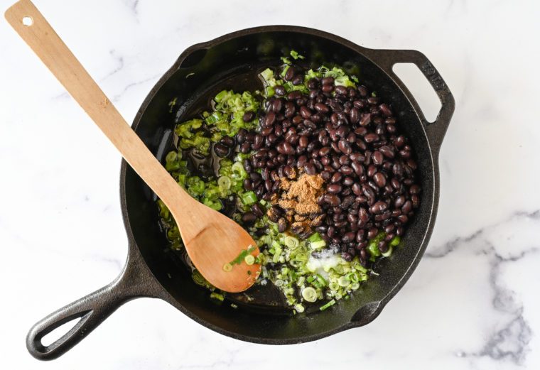 adding beans, water and seasoning to skillet