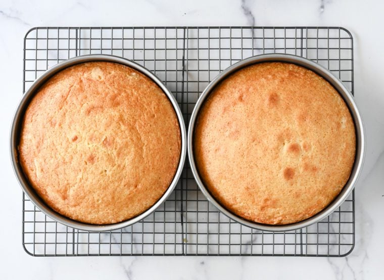 Two round cake pans on a wire rack.