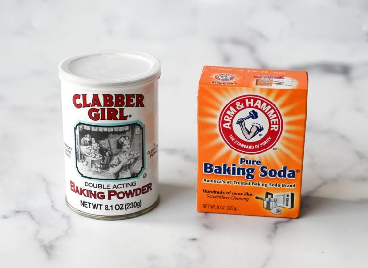 Container of baking powder next to a box of baking soda.