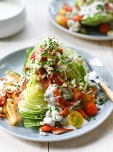Wedge salad with blue cheese dressing on a plate with a fork.