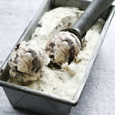 Ice cream scoop in a container of Oreo cheesecake ice cream.