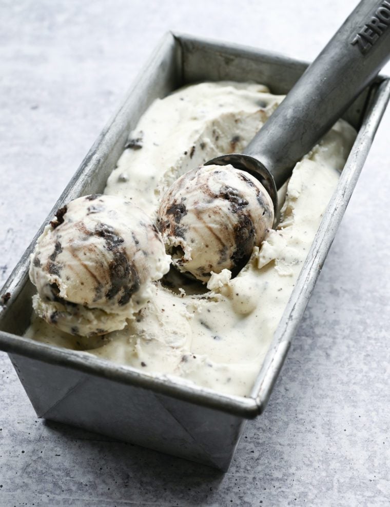Ice cream scoop in a container of Oreo cheesecake ice cream.