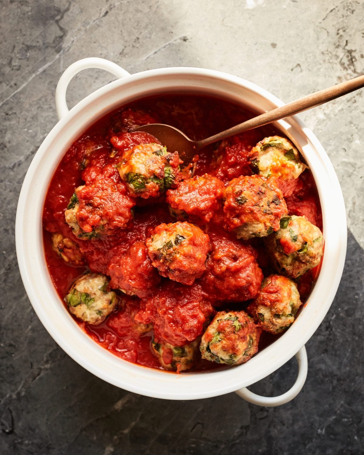 Spoon in a dish of turkey spinach meatballs.