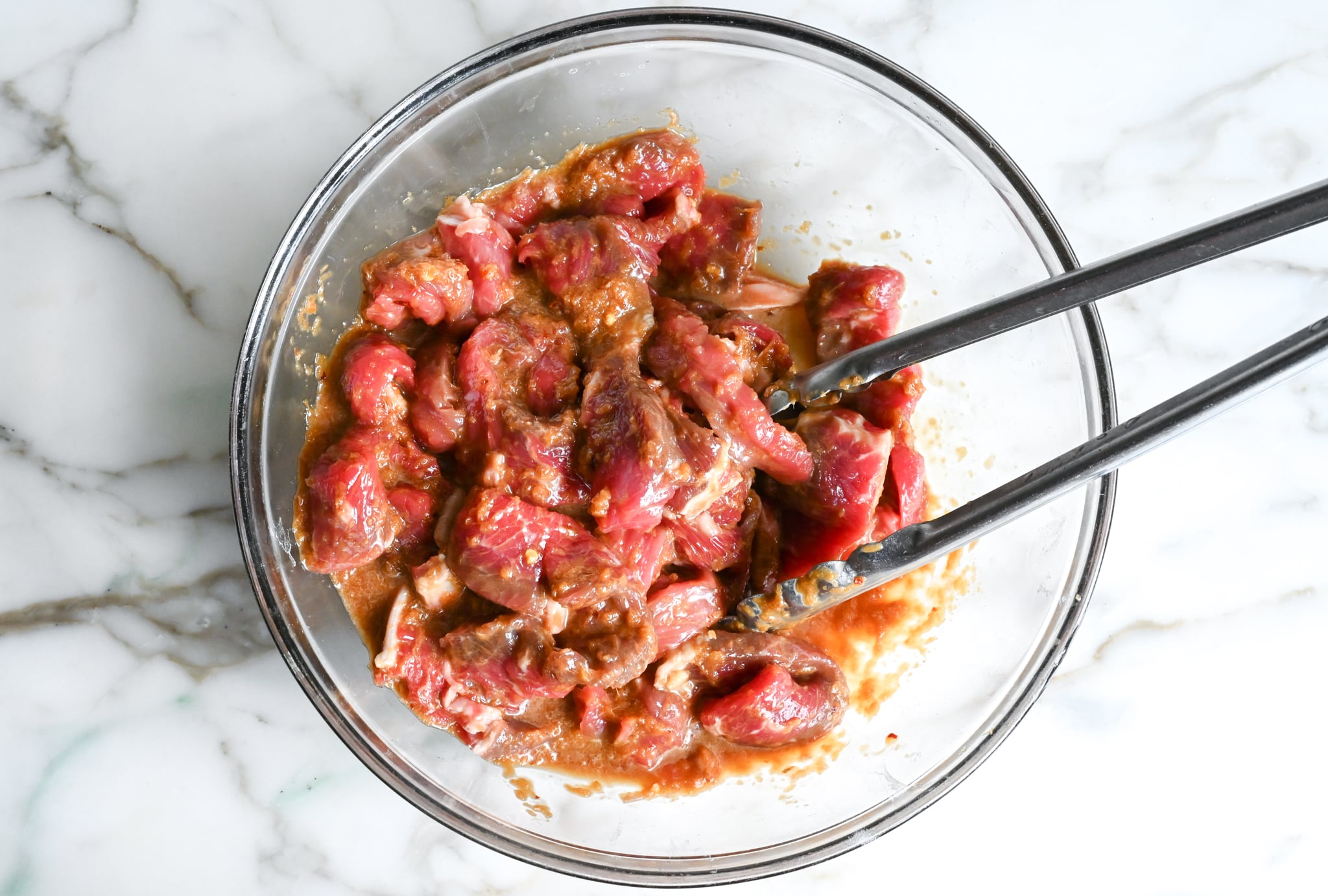 Tossing sliced meat with bulgogi marinade.