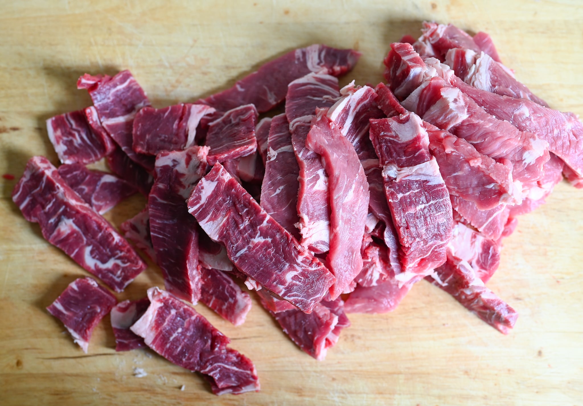 Thinly sliced rib-eye on cutting board.