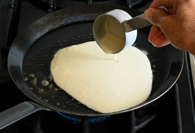 pouring the crepe batter into the pan.