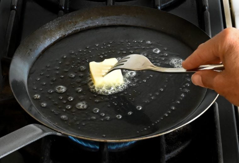 greasing the crepe pan with butter.