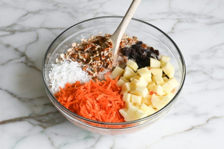 adding carrots, coconut, pecans, apples and raisins to oat mixture