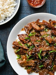 Beef bulgogi on platter with rice and hot sauce on the side.