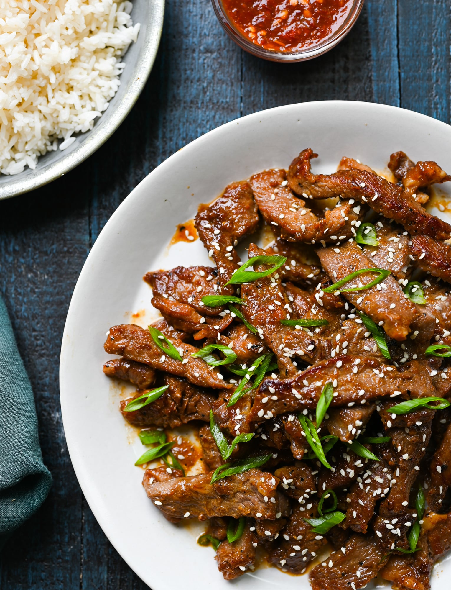 Beef bulgogi on platter with rice and hot sauce.
