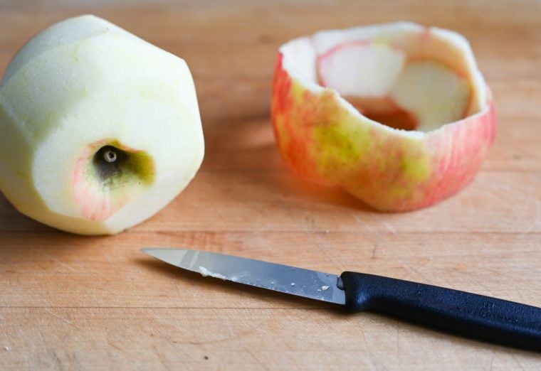 Paring knife with a peeled apple and an apple peel.