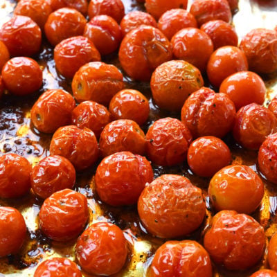 Roasted cherry tomatoes on a lined baking sheet.