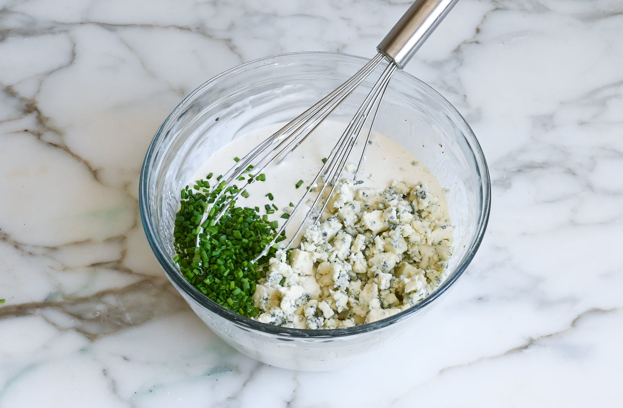 Adding blue cheese and chives to the blue cheese dressing base.