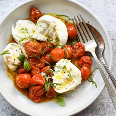 Plate of slow-roasted cherry tomatoes and burrata.