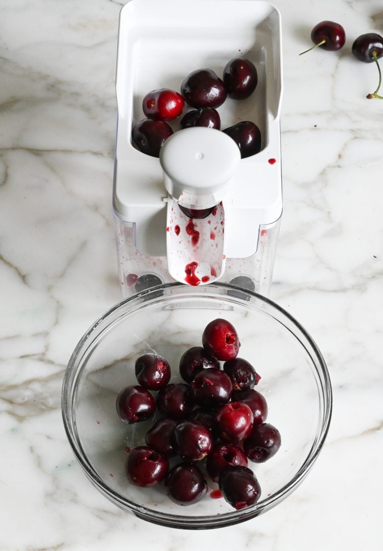 Cherries going through a cherry pitter.