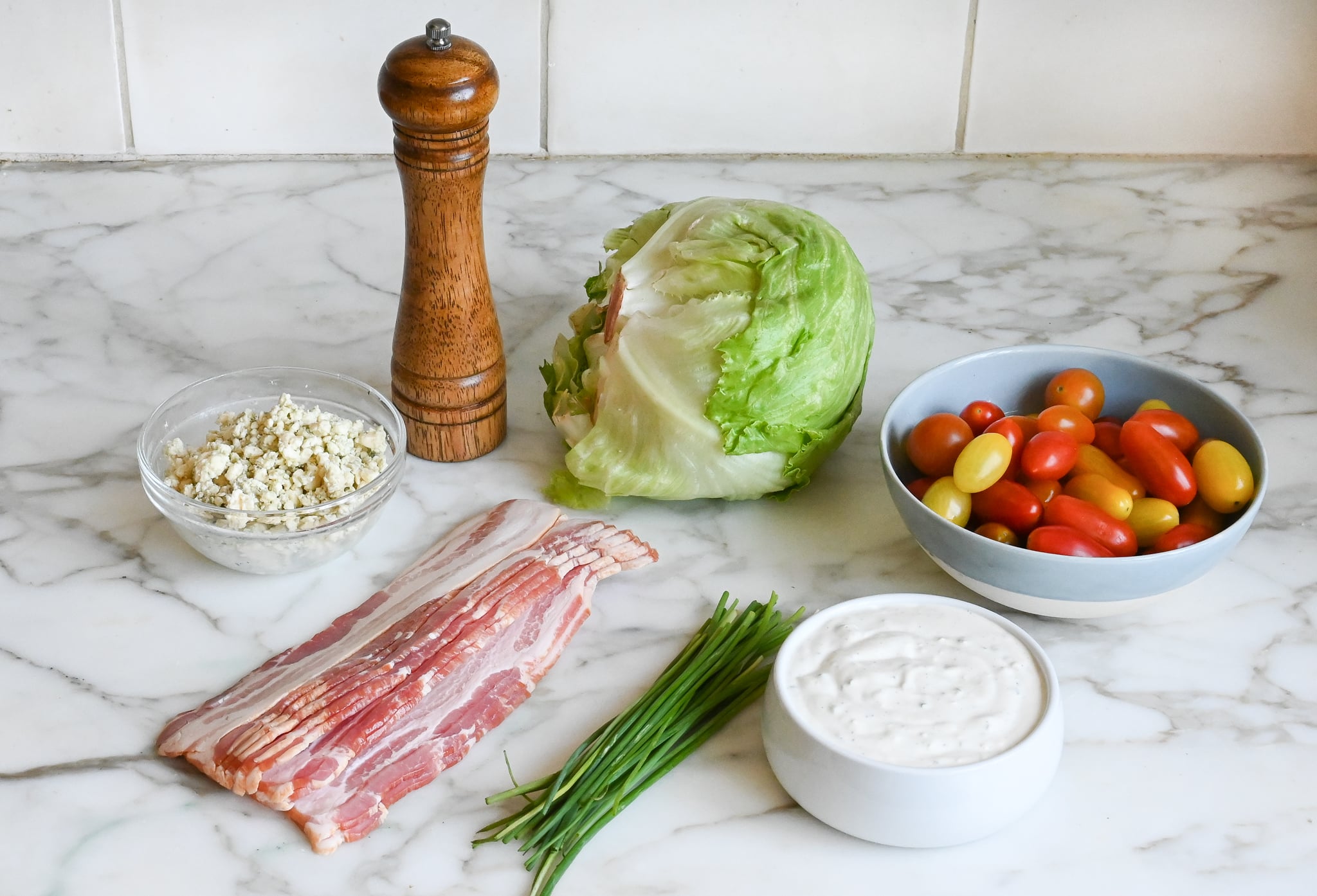 Ingredients to make wedge salad with blue cheese dressing in a bowl on the counter.