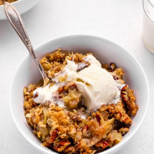 apple crisp in bowl with vanilla ice cream