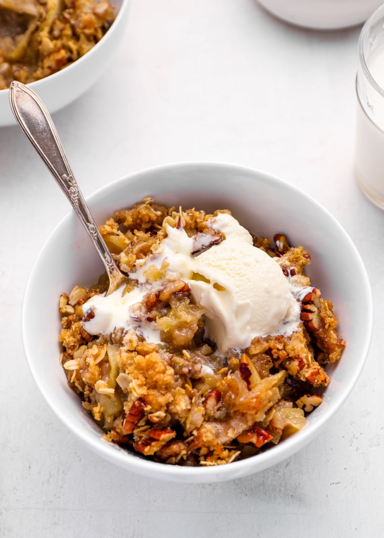 apple crisp in bowl with vanilla ice cream