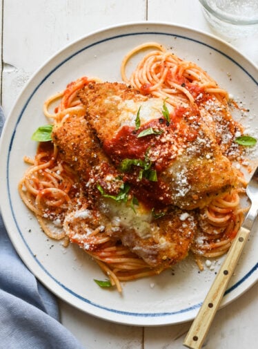 plate of chicken parmesan over spaghetti