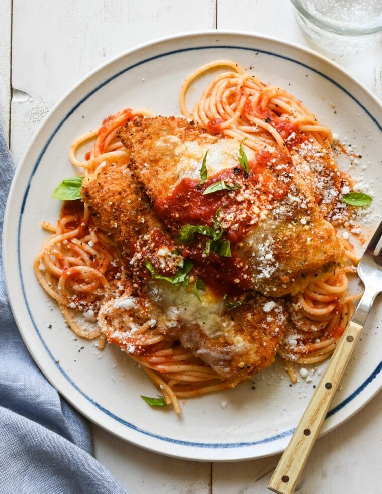 plate of chicken parmesan over spaghetti