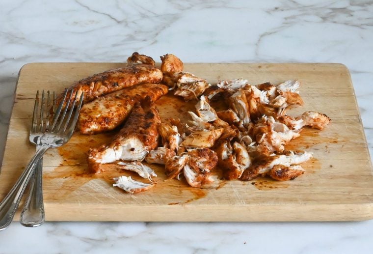 shredding the chicken on a cutting board
