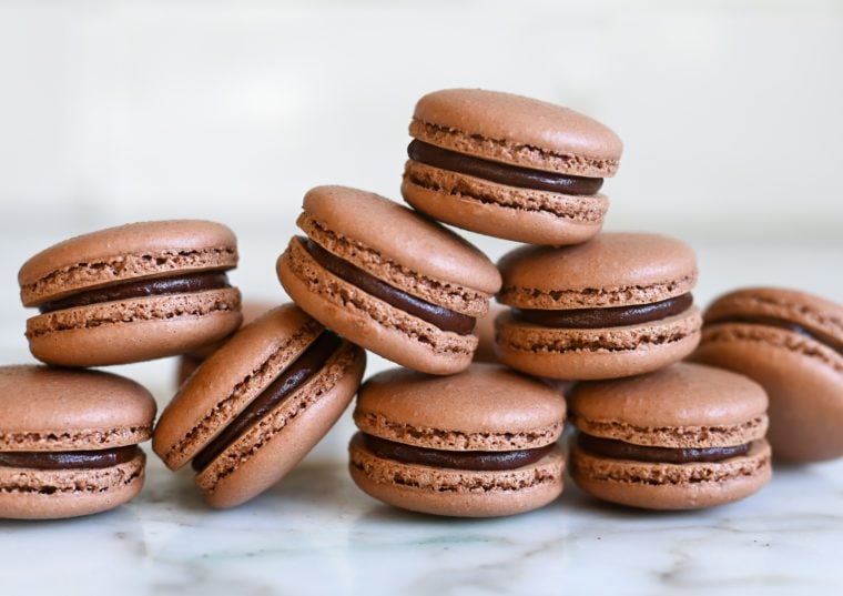 chocolate macarons stacked on white marble