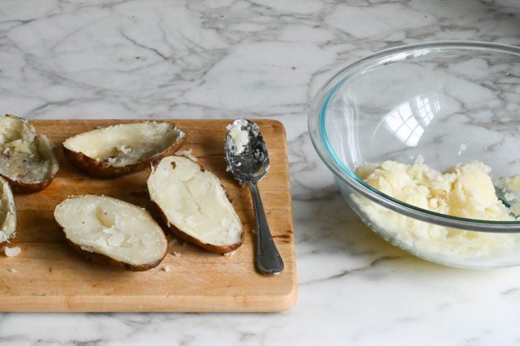 scooping flesh from potatoes