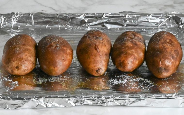 Baked potatoes on a lined baking sheet.