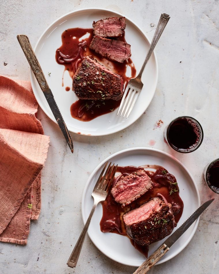 Glasses of red wine with plates of barbeque.