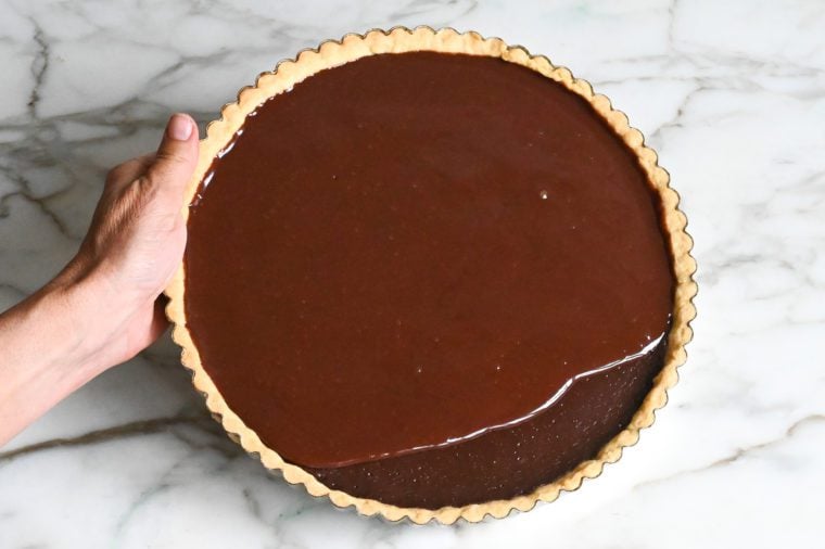 tilting the tart pan to spread the chocolate glaze