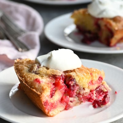 Nantucket cranberry pie on plates with whipped cream.