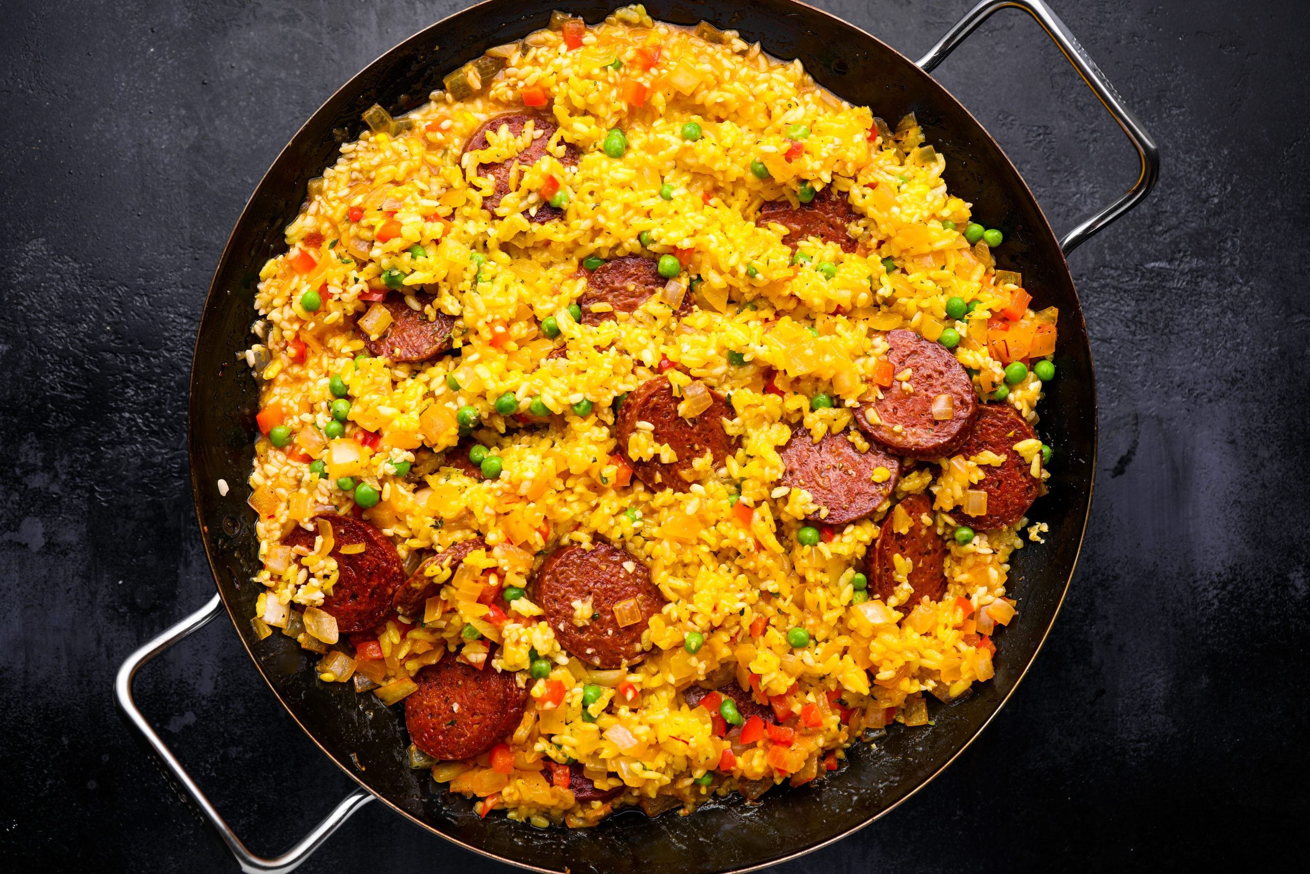 Cooked rice with peas, chorizo, and thyme in the pan.