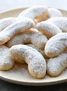Snowball cookies shaped like crescents piled on a plate.