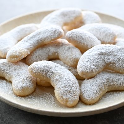 Snowball cookies shaped like crescents piled on a plate.