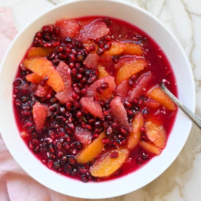 Spoon in a bowl of citrus and pomegranate fruit salad.