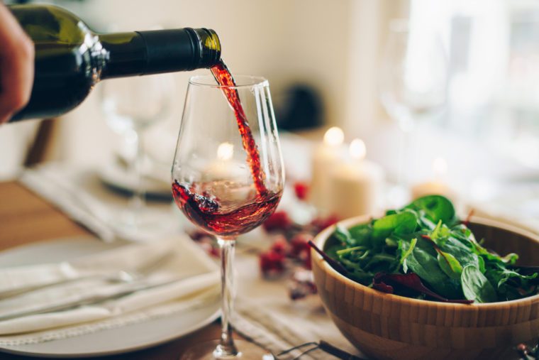Bottle pouring pinot noir into a glass.