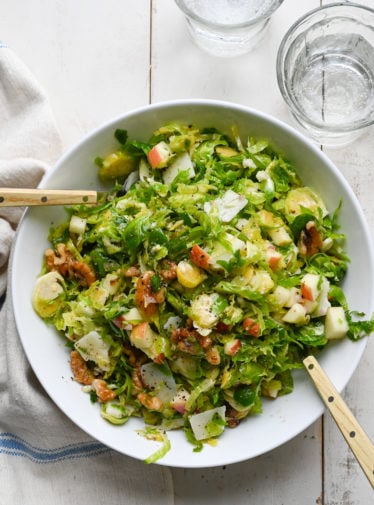 Large bowl of brussels sprout salad with apples, walnuts and parmesan.