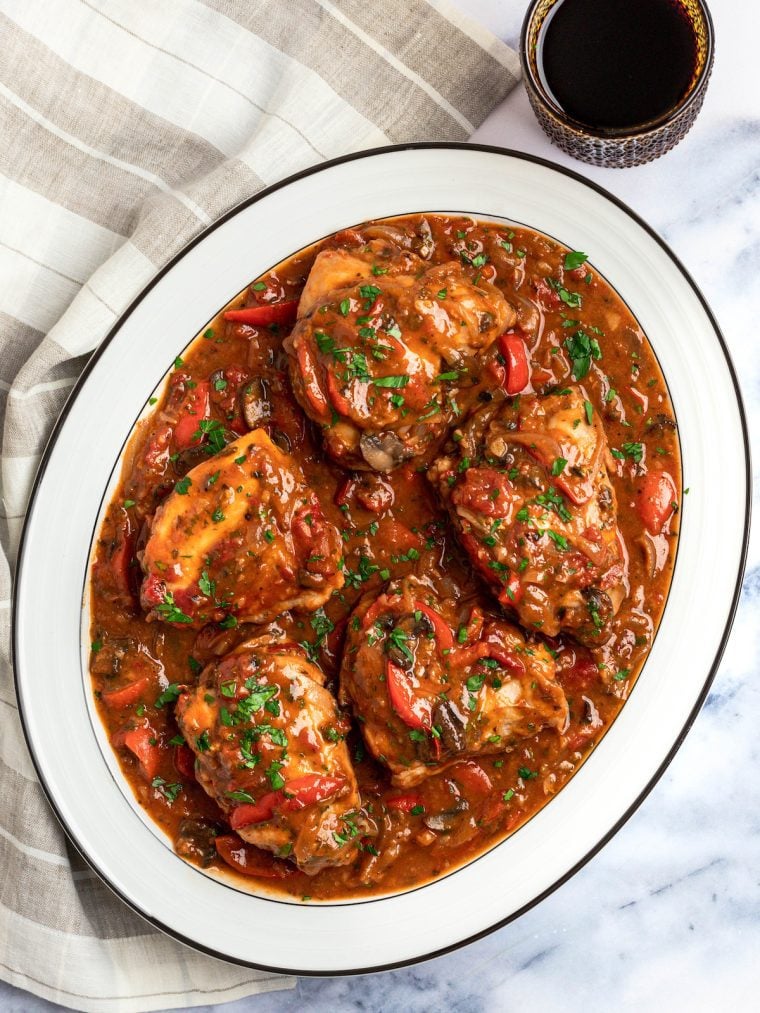 chicken cacciatore on a platter with glass of wine.