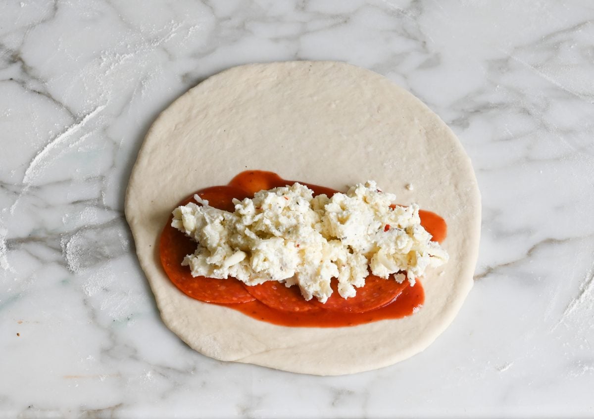 sauce, pepperoni, and cheese mixture on dough
