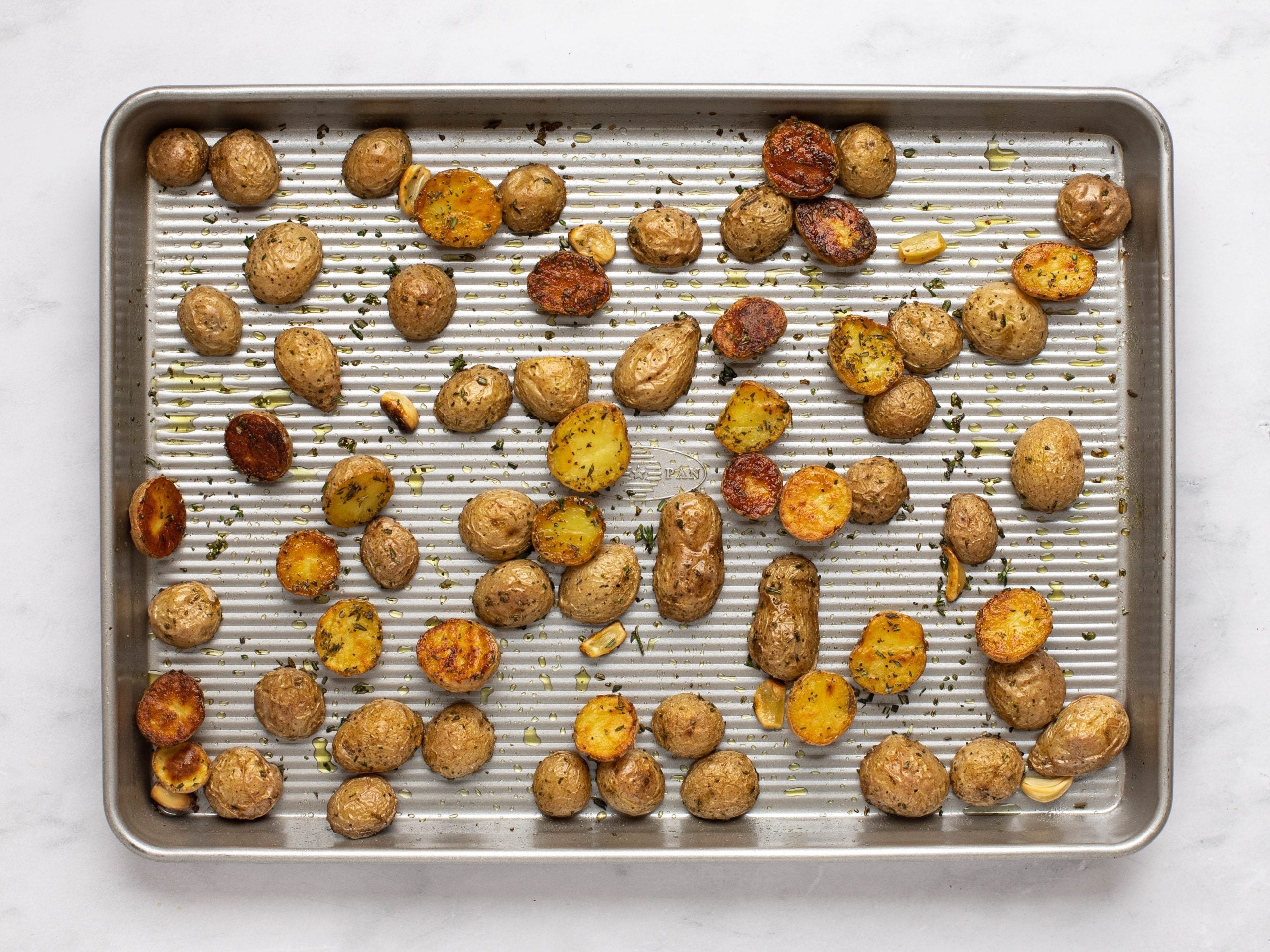Golden brown roasted potatoes on a baking tray.