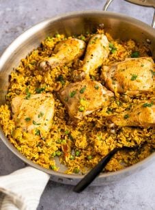 Spoon in a skillet of arroz con pollo.