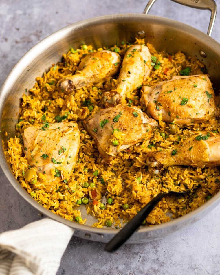 Spoon in a skillet of arroz con pollo.