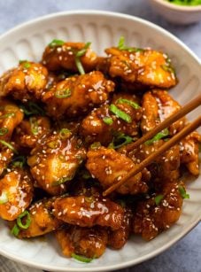 Chopsticks grabbing a piece of General Tso's chicken.