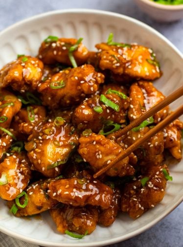 Chopsticks grabbing a piece of General Tso's chicken.