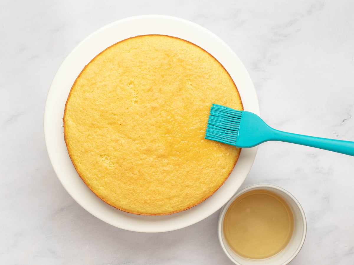 brushing soaking syrup onto cake