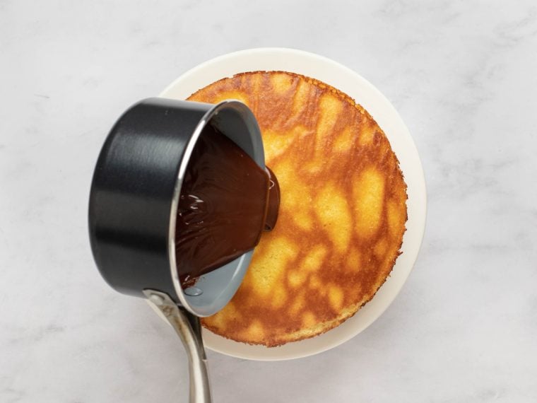 pouring ganache onto cake