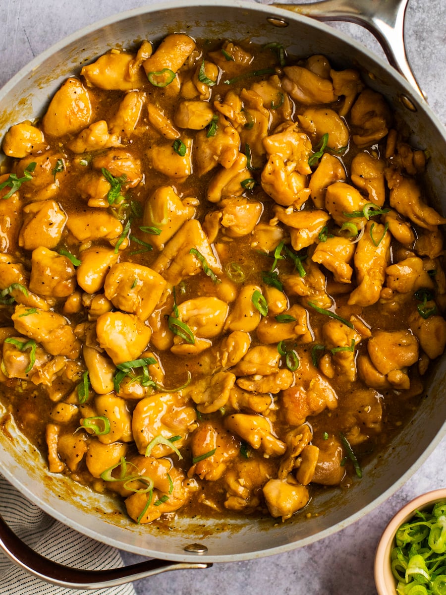bourbon chicken in skillet topped with scallions.